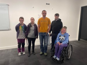 Group shot of 5 people including Blind climbers and a wheelchair user at the front of a lecture room