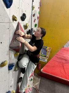 A climber side-pulls on a volume, looking up for her next hold.