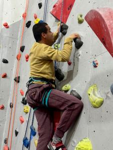 Ryan works his way up the wall, grasping holds with each hand and feeling for a foot hold, positioned for a strong upwards push. 