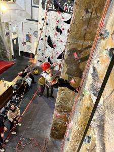 Another thumbs up as young climber confidently abseils, his belayers below letting out the rope. 